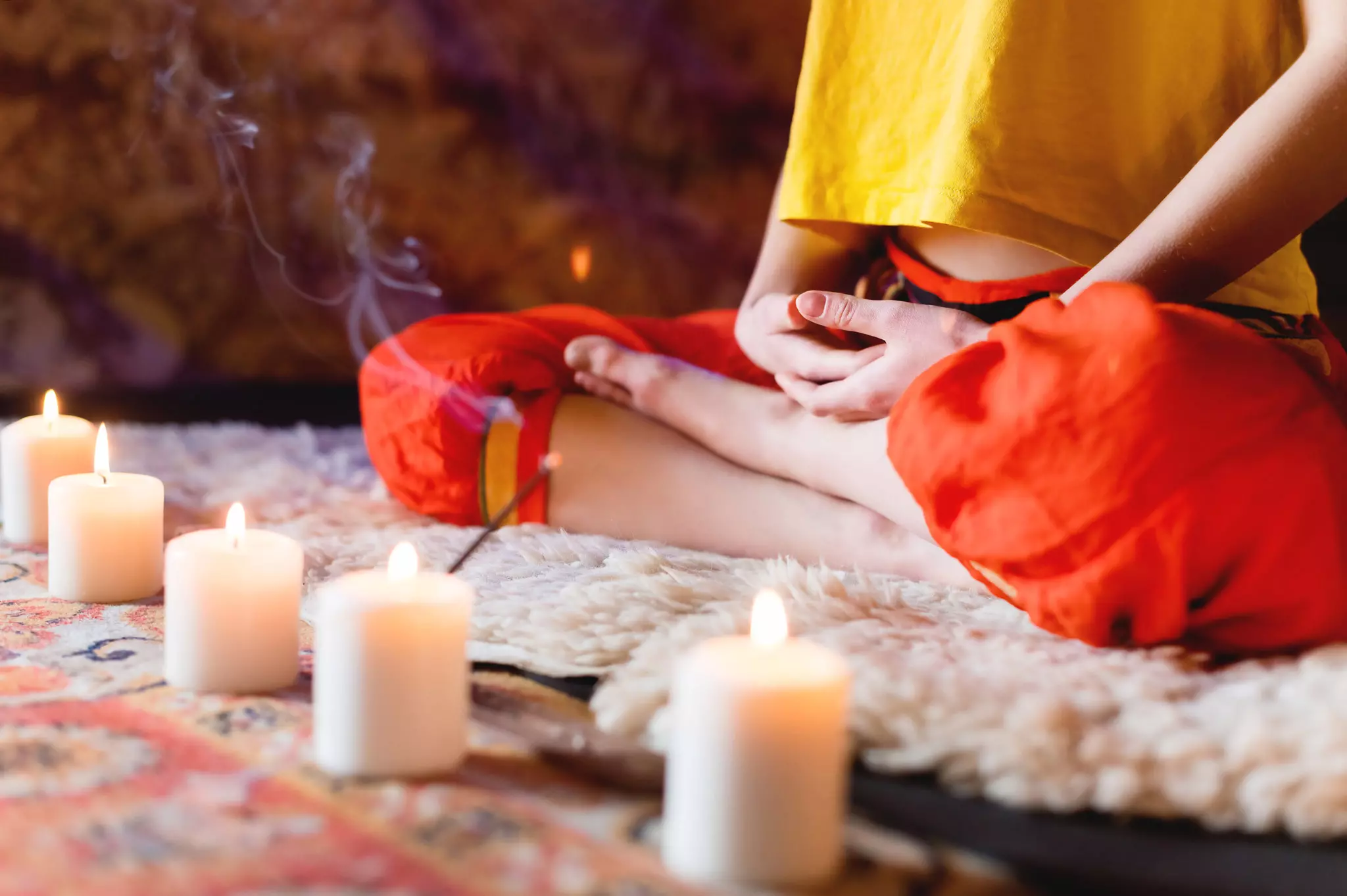 Frau im Meditationssitz mit Kerzen und Räucherwerk